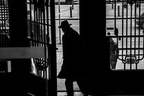 A man's silhouette exiting through wraught metal gates von Jessy Libik