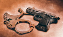 Gun and handcuffs on table. Photo in old color image style von Serhii Zhukovskyi