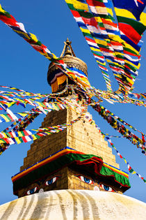 Prayer flags in the wind at the Boudhanath Stupa. by Tom Hanslien