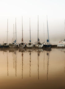 Boats moored to bridge in foggy weather by Arletta Cwalina
