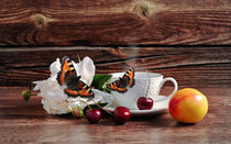 Coffee, cherry, flower and butterfly on a wooden background von larisa-koshkina