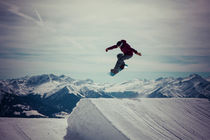 Snowboarder springt vor gewaltiger Bergkulisse by hummelos