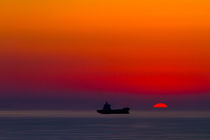 Silhouette of a ship on the ocean at red sunset with half sun ball at the horizon by Sharon Yanai