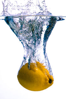 Lemon falls into water with big splash on white background. Taken at the studio. Motion and hi-speed photography by Sharon Yanai