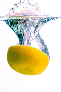 Grapefruit falls into water with big splash on white background by Sharon Yanai