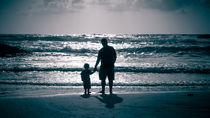 Father and Son on the beach at dusk by Sharon Yanai