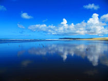 Weiße Wolken spiegeln sich im Wasser am Ninety Mile Beach in Neuseeland von nadini