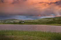 Huts on lake in landscape of Norway during sunset by Bastian Linder