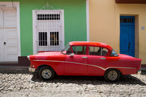 Red old car in front of colourful houses, Cuba von Bastian Linder
