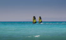 Two windsurfers ride parallel in sea by Bastian Linder