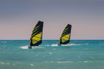 Two windsurfers ride parallel in sea by Bastian Linder