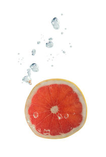 Grapefruit in water with air bubbles by Bastian Linder