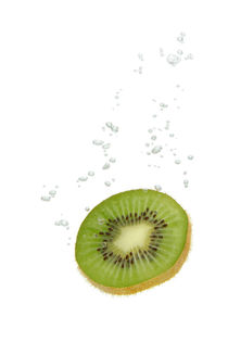 Kiwi fruit in water with air bubbles by Bastian Linder