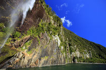 A tall waterfall drops off a steep cliff into the waters of ... von Danita Delimont