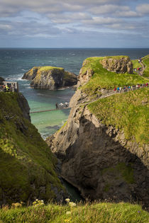Tourists walk across the Carrick-a-Rede Rope Bridge along th... by Danita Delimont