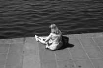 Eine Frau sitzt in sich versunken am Wasser. by fischbeck
