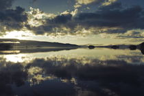 Towering clouds are reflected in a glassy lake at sunset by Intensivelight Panorama-Edition