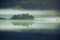 MIst  rising over a small wooded island is reflected in a glassy lake in fall by Intensivelight Panorama-Edition