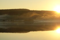 Wisps of haze are rising from a forest at the shore of a glassy lake at sunset von Intensivelight Panorama-Edition