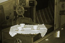 Flower patterned tea cups are laid out on a doily near the helm of a vintage wooden boat - sepia von Intensivelight Panorama-Edition