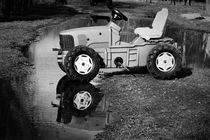 Abandoned toy tractor in a puddle by Maud de Vries