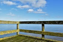 Weathered jetty with river and sky with clouds by Maud de Vries