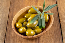 Grüne Oliven mit Zweig in einer Holzschale - Green olives with twig in a wooden bowl by Thomas Klee