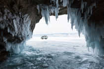 Blick aus einer vereisten Felshöhle auf den Baikalsee mit parkendem UAZ