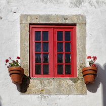 Ein rotes Fenster in einer weißen Hauswand von Berthold Werner