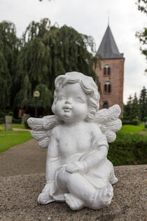 Engelfigur sitzt vor einer Kirche von ollipic