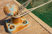 detail of a bollard with chains and ropes for mooring at the harbor by susanna mattioda
