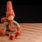 Handmade-crochet-autumn-gnome-with-red-hat-and-scarf-sitting-position