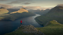 Man at Hvithamar near the town of Gjogv on the Faroe island of Eysturoy with a panoramic view of the fjord at sunset by Bastian Linder