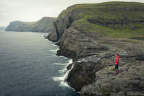 Woman on coast, waterfall and cliffs at Trælanípa on the island of Vagar, on Lake Leitisvatn, Faroe Islands by Bastian Linder