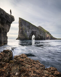 Person in front of Drangarnier rock formations on Vagar, Faroe Islands by Bastian Linder