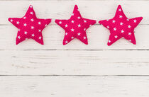 Three pink stars decoration on white wooden background by Alex Winter