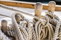 Moored ropes on wooden cleats on old sailing boat, closeup von Alex Winter