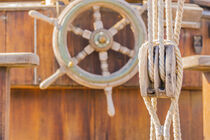 Old sailing boat deck with nautical pulley and vintage wooden helm wheel by Alex Winter