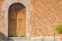 Stone wall background with old wooden front door of rustic house by Alex Winter