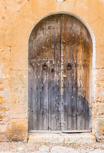 Old gray wooden front door of a mediterranean house entrance, close-up von Alex Winter