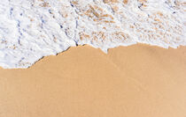 Sand beach background with sea wave foam close-up by Alex Winter