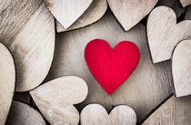 One red love heart between many wooden hearts by Alex Winter