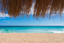 Empty sand beach with turquoise sea water, sun, blue sky and straw umbrella by Alex Winter