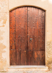 Brown wooden front door of mediterranean residence entrance von Alex Winter