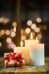 Three white christmas candles with sparkling light background by Alex Winter
