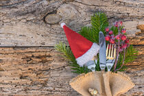 Advent or Christmas table place setting with santa cap on rustic wood by Alex Winter