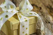 Christmas gift with golden star shaped ribbon bow on wood background by Alex Winter
