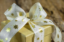 Christmas present with golden star shaped ribbon bow by Alex Winter