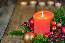 Burning red candle flame for Advent and Christmas with fir branches and baubles arrangement by Alex Winter