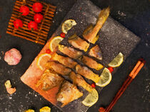Fischgericht. Zubereiteter Fisch auf Holzbrett mit Zitrone und Tomate. Gemalt. von havelmomente